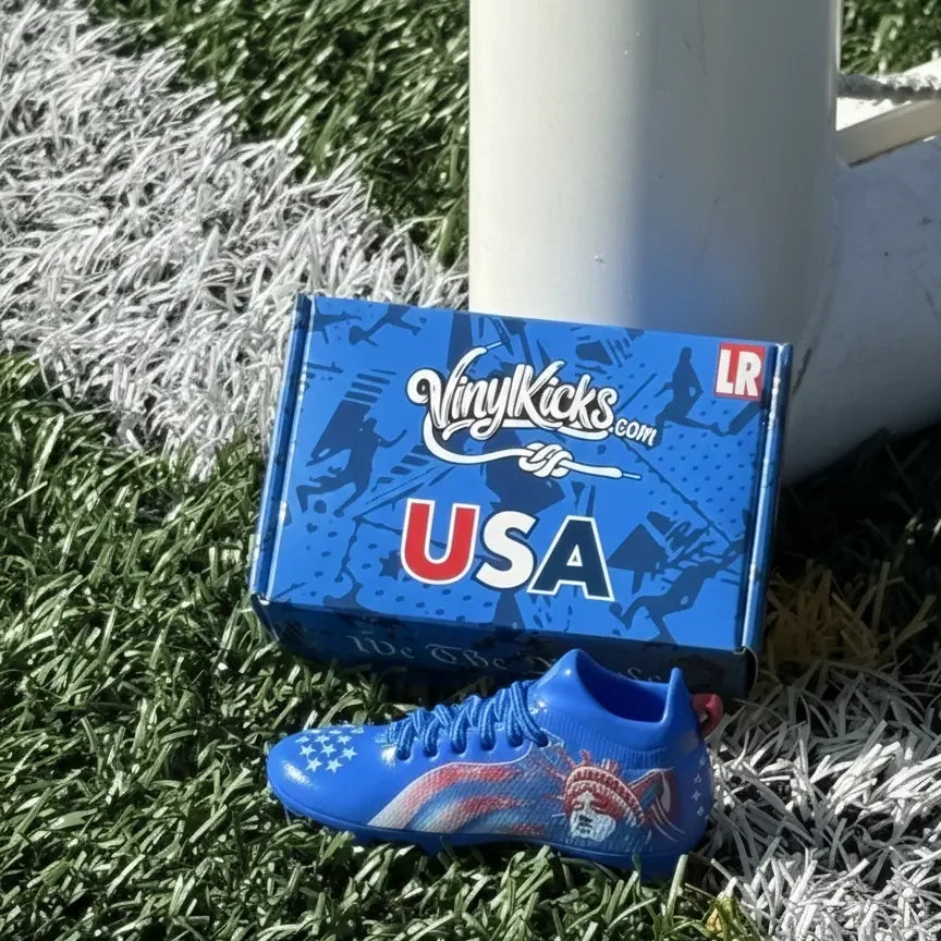 Miniature USA soccer shoe collectible and blue box on turf, bag charm accessory
