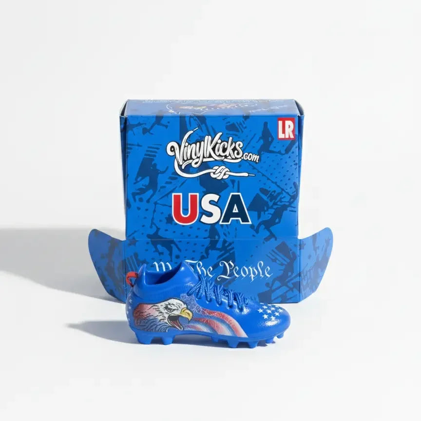 Miniature collectible blue soccer shoe with USA flag and eagle design, in front of a USA-themed gift box.